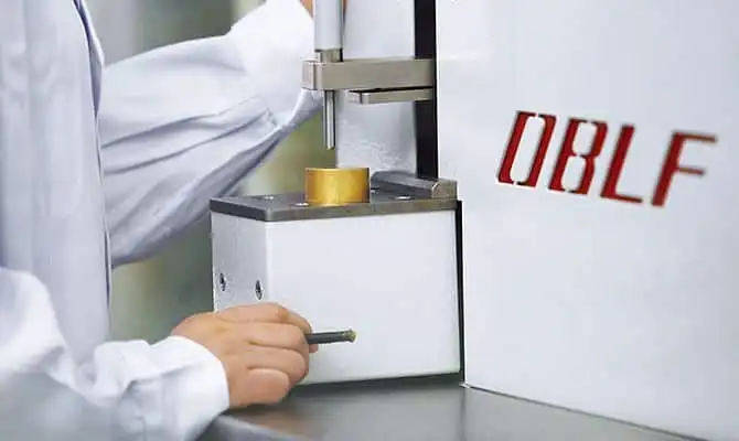 A scientist operating an OBLF spectrometer to analyze a metal sample.