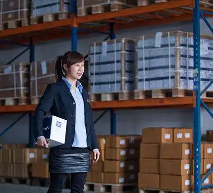 A warehouse supervisor inspecting inventory with a clipboard in hand.